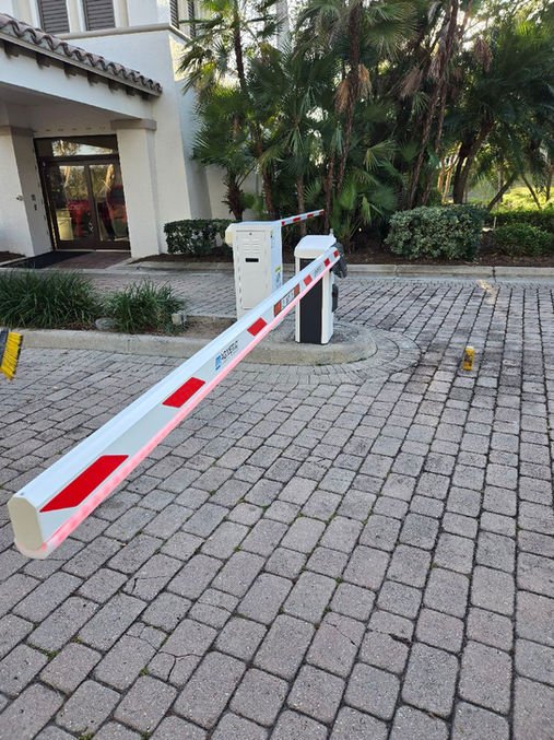 Vehicle barrier arm beside a paved property entrance.